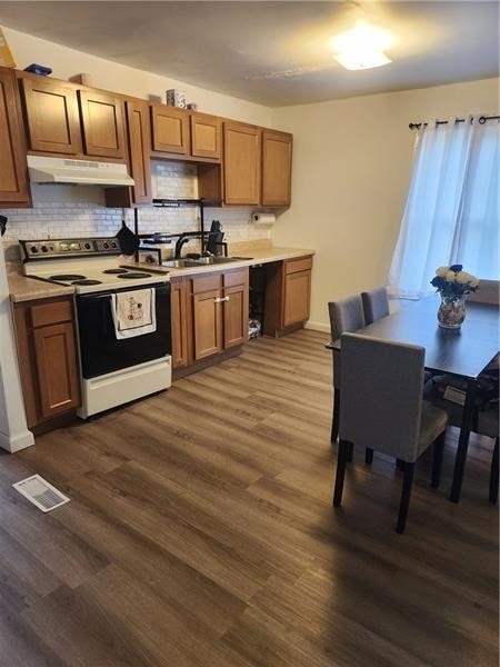 kitchen with white range with electric cooktop, sink, dark wood-type flooring, and backsplash