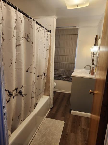 full bathroom with vanity, toilet, shower / bathtub combination with curtain, and hardwood / wood-style flooring