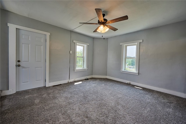 empty room featuring ceiling fan, carpet, and a healthy amount of sunlight