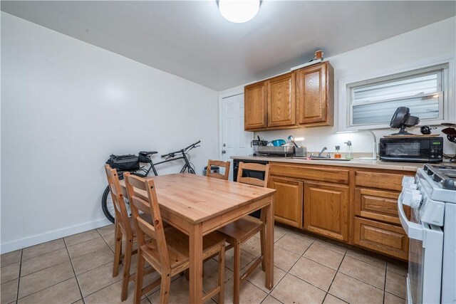 kitchen featuring light tile patterned flooring, white gas stove, and sink