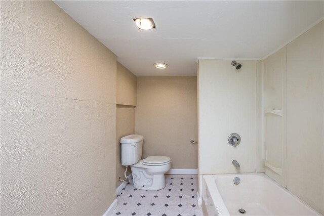 bathroom featuring washtub / shower combination, tile patterned floors, and toilet