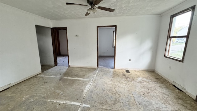 empty room with ceiling fan, crown molding, and baseboards
