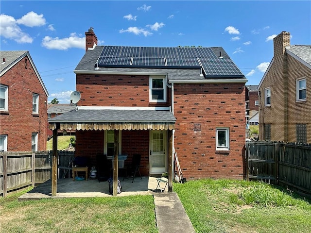 back of house featuring a yard, a patio, and solar panels