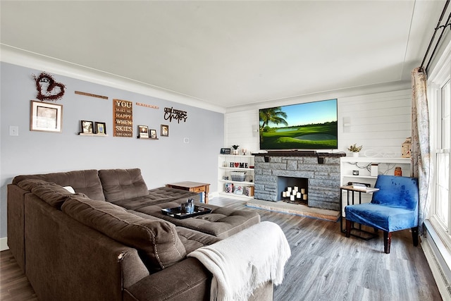 living room featuring a stone fireplace, hardwood / wood-style flooring, and baseboard heating