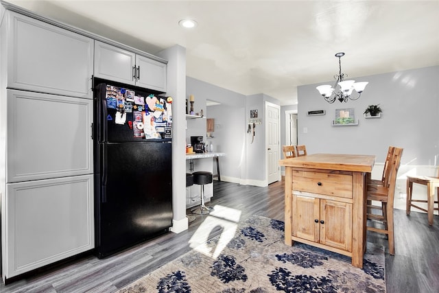 kitchen with a notable chandelier, dark hardwood / wood-style flooring, black fridge, pendant lighting, and gray cabinetry