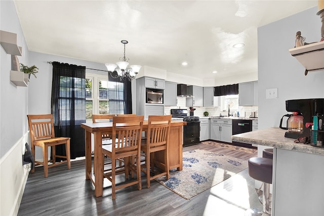 dining area with a notable chandelier, sink, and dark wood-type flooring