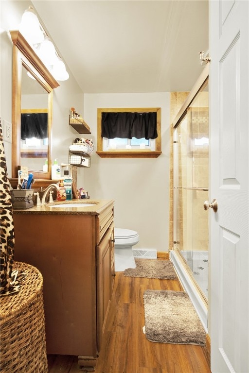 bathroom with walk in shower, wood-type flooring, toilet, and vanity