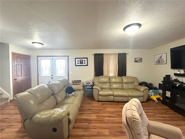 living room with a textured ceiling, french doors, and hardwood / wood-style floors