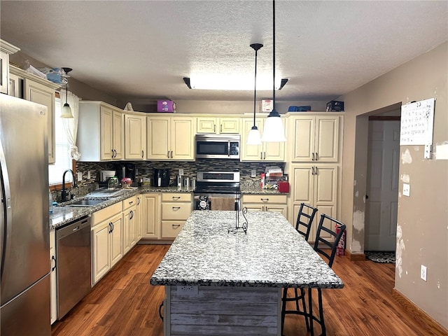 kitchen featuring a kitchen island, cream cabinets, dark hardwood / wood-style floors, appliances with stainless steel finishes, and sink