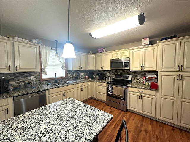 kitchen with stainless steel appliances, stone counters, sink, dark hardwood / wood-style floors, and backsplash