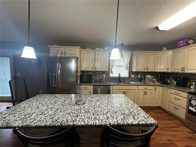 kitchen with stainless steel appliances, hardwood / wood-style floors, sink, decorative backsplash, and light stone countertops