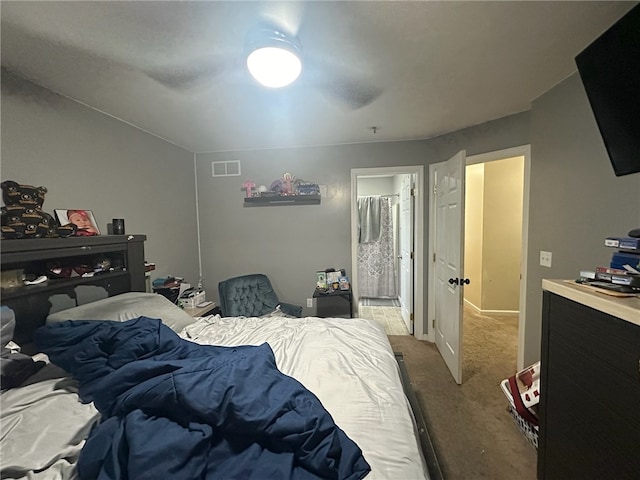 carpeted bedroom with ensuite bath and ceiling fan