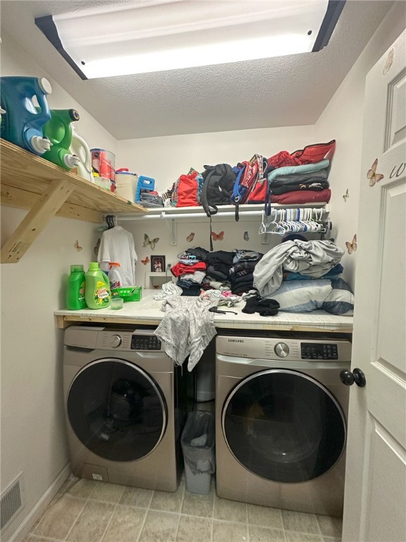 washroom with separate washer and dryer, light tile patterned flooring, and a textured ceiling