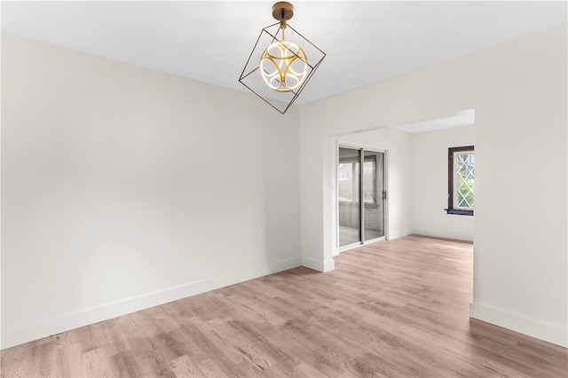 empty room with light hardwood / wood-style flooring and an inviting chandelier