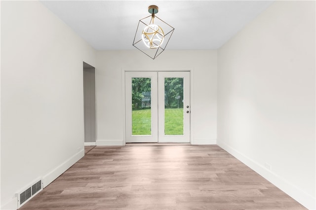 unfurnished room featuring hardwood / wood-style flooring and a chandelier