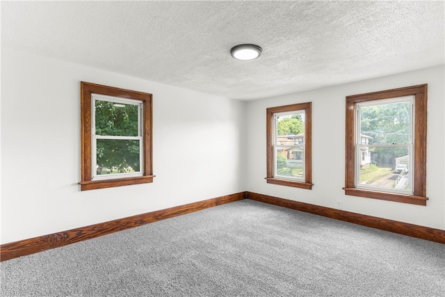 carpeted empty room with a textured ceiling