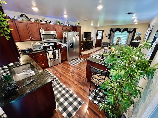 kitchen featuring dark stone countertops, stainless steel appliances, dark hardwood / wood-style floors, and sink