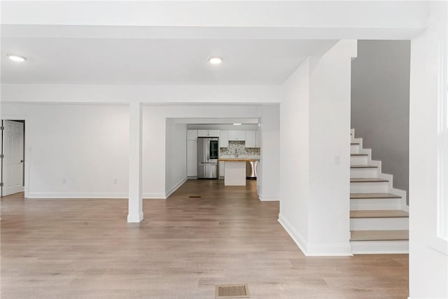 interior space featuring visible vents, baseboards, stairs, light wood-type flooring, and smart refrigerator