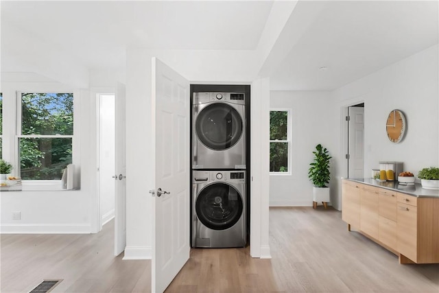 laundry room featuring laundry area, light wood-type flooring, visible vents, and stacked washer / drying machine