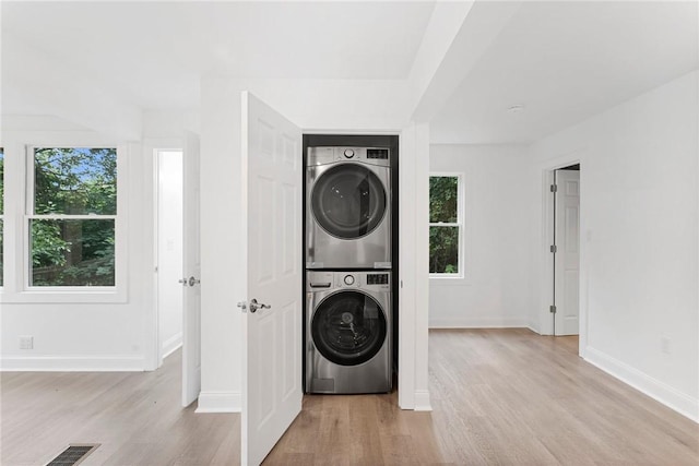 clothes washing area with laundry area, visible vents, a wealth of natural light, and stacked washer / drying machine