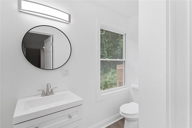 bathroom with wood finished floors, vanity, toilet, and baseboards