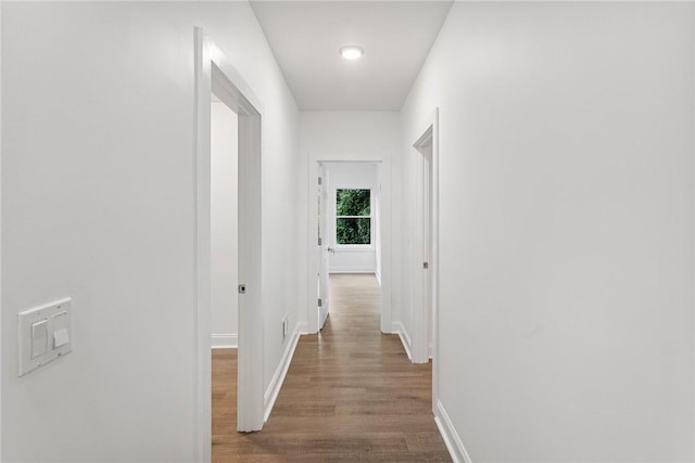 hall with baseboards and wood finished floors