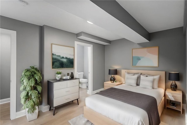 bedroom with light wood-type flooring, baseboards, and ensuite bathroom