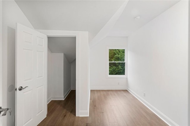 unfurnished bedroom with vaulted ceiling, baseboards, and wood finished floors