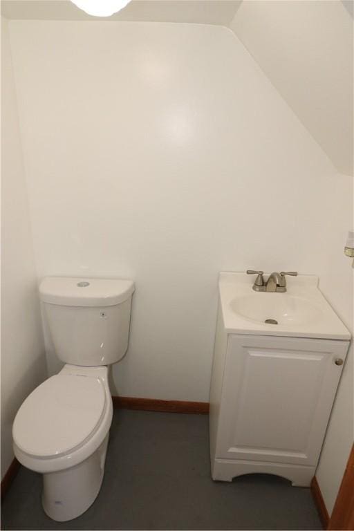 half bathroom with toilet, baseboards, vaulted ceiling, and vanity