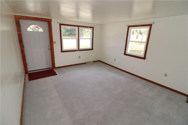 foyer featuring light carpet, plenty of natural light, visible vents, and baseboards