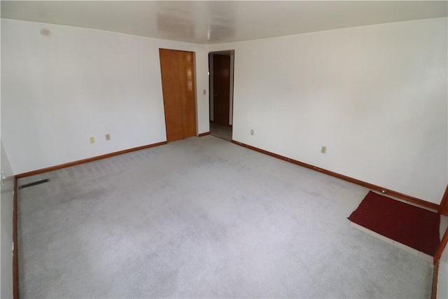 empty room featuring light carpet and baseboards