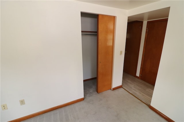 unfurnished bedroom with light carpet and a closet