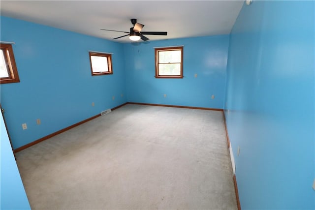 unfurnished room with baseboards, a ceiling fan, visible vents, and light colored carpet