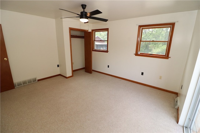 unfurnished bedroom with light colored carpet, a closet, and ceiling fan