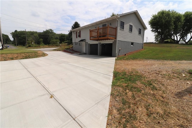 view of front of house featuring driveway, a deck, a garage, and a front lawn