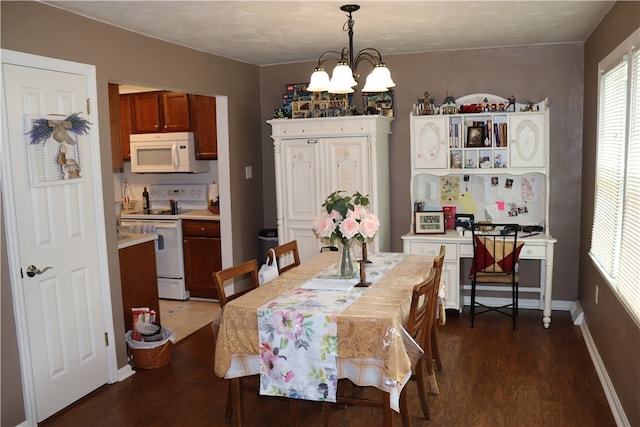 dining room with dark wood-type flooring and an inviting chandelier