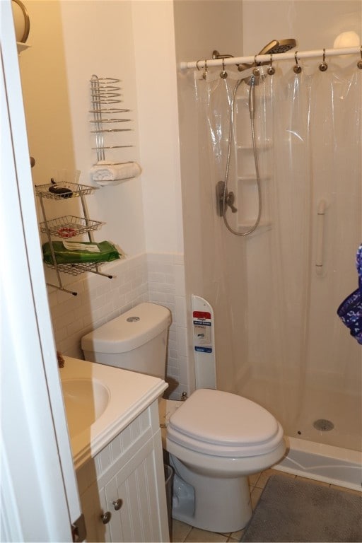 bathroom featuring tile patterned flooring, walk in shower, toilet, vanity, and tile walls