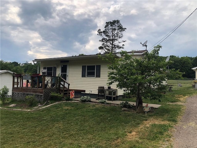 view of front of home with a wooden deck, a patio, and a front yard