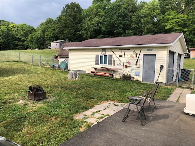 back of house featuring an outbuilding, a yard, and a patio