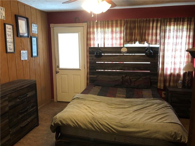 bedroom with dark colored carpet and wooden walls