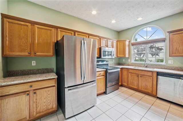 kitchen featuring light tile patterned floors, stainless steel appliances, sink, and a textured ceiling