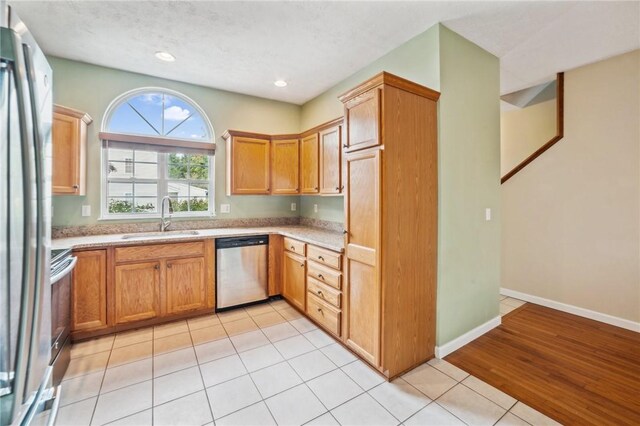 kitchen with stove, sink, dishwashing machine, light hardwood / wood-style floors, and refrigerator