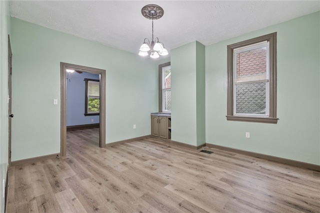 interior space with a wealth of natural light, a chandelier, and light hardwood / wood-style floors