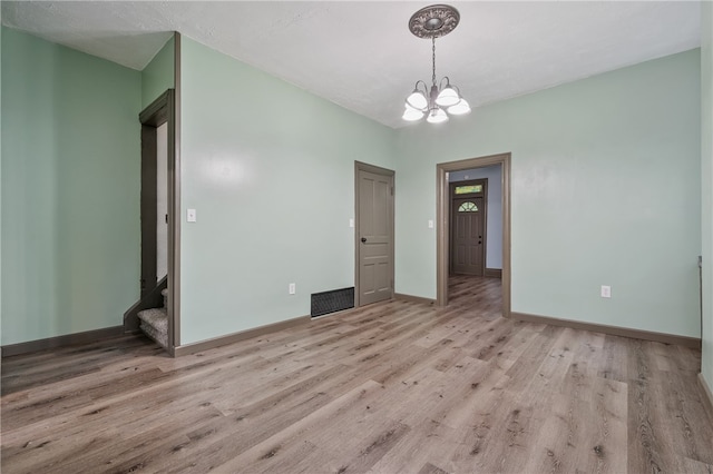 empty room with hardwood / wood-style floors and a chandelier