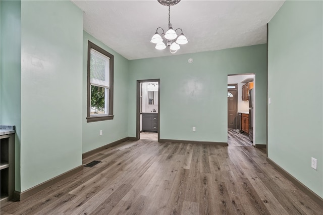 interior space featuring wood-type flooring, connected bathroom, and an inviting chandelier