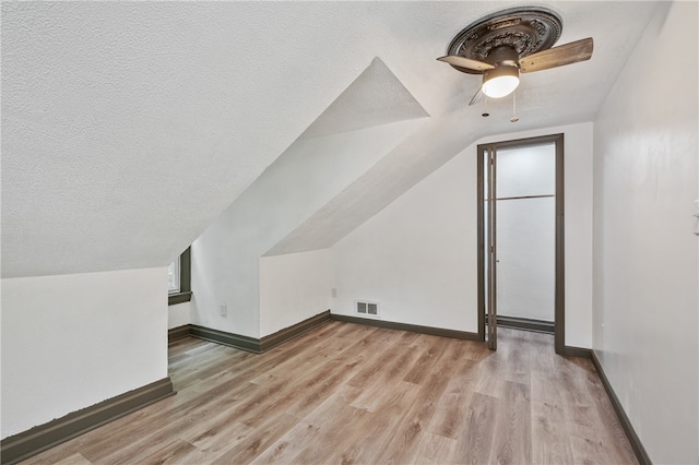 bonus room with light hardwood / wood-style floors, a textured ceiling, ceiling fan, and vaulted ceiling