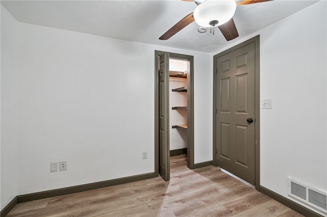 unfurnished bedroom with ceiling fan, light hardwood / wood-style floors, a closet, and a spacious closet