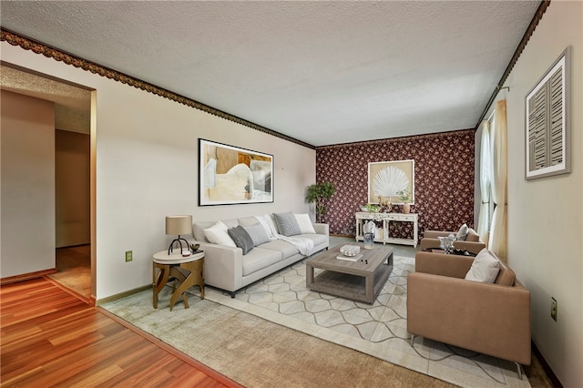 living room with light hardwood / wood-style flooring, a textured ceiling, and ornamental molding