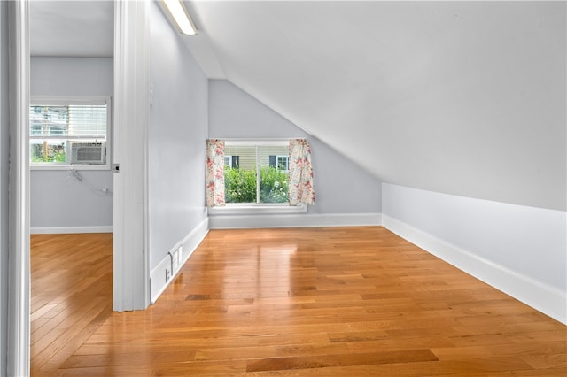 additional living space featuring lofted ceiling, light hardwood / wood-style flooring, and cooling unit