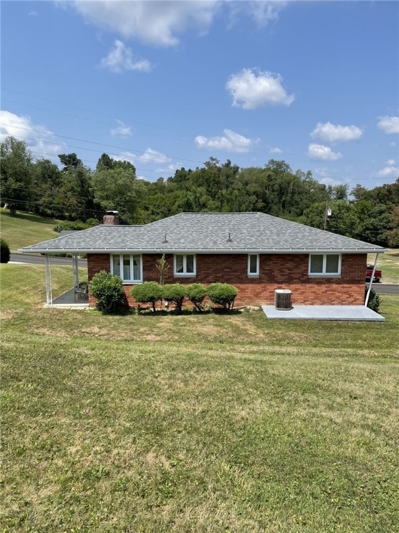 rear view of property with cooling unit, a yard, and a patio area